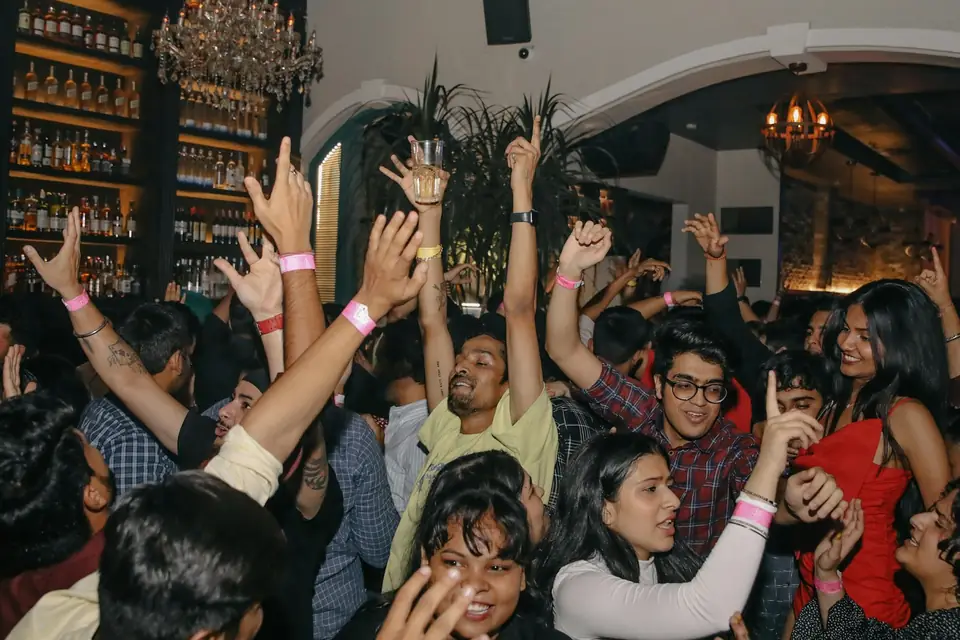 A crowded party, everyone dancing with their hands in the air